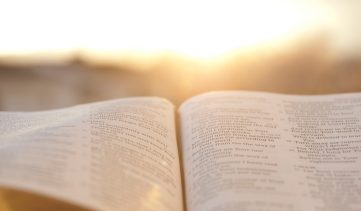 Open Bible with bright sunset in the background.